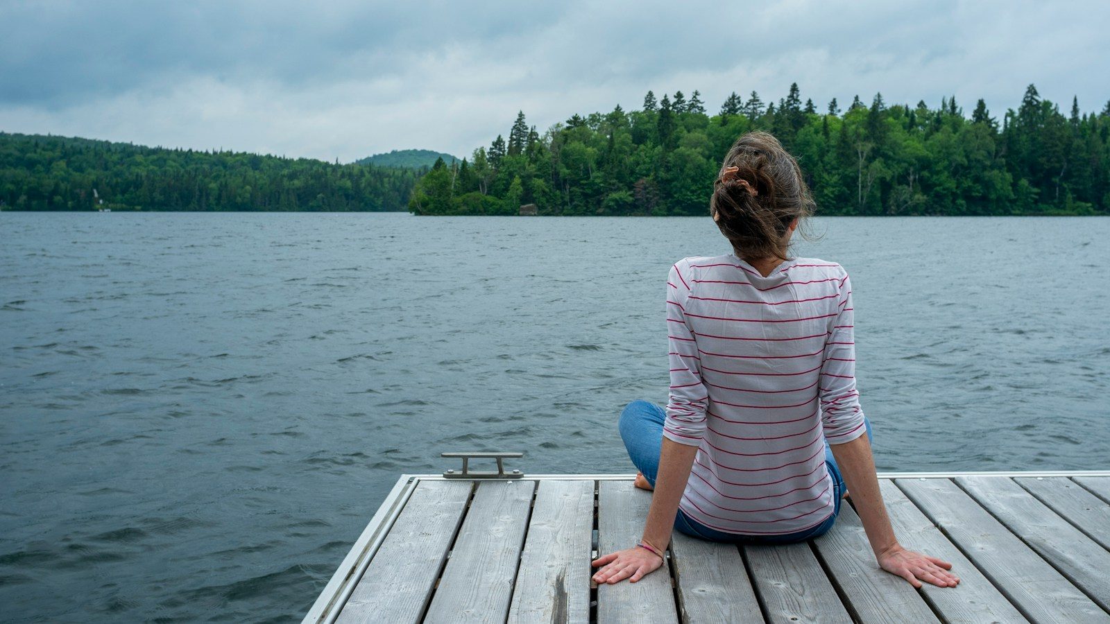 a woman sitting on a dock looking at the water