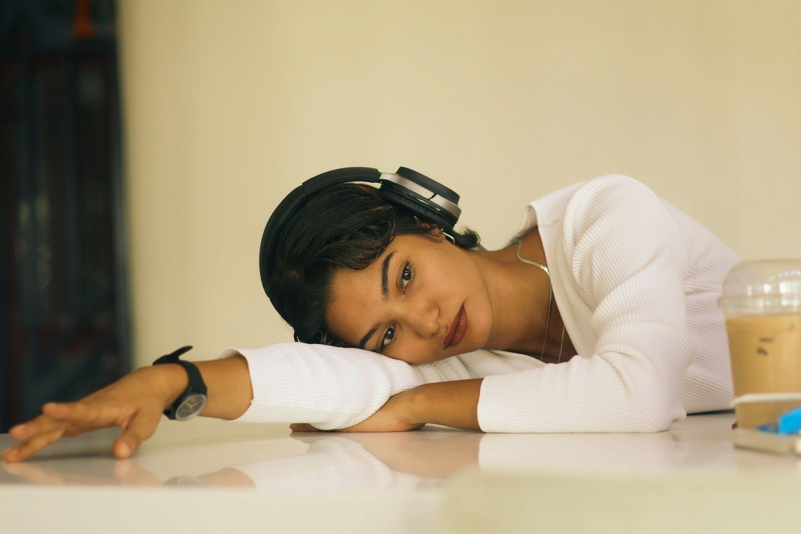 Young woman with headphones rests head on desk
